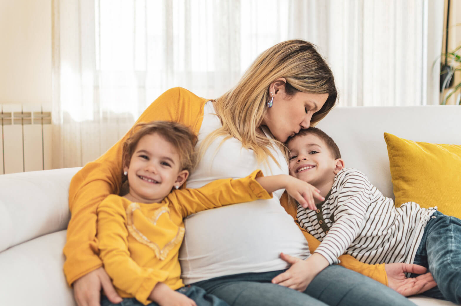 Happy mother and children,a boy and a girl are embracing pregnant belly with excitement on their faces.