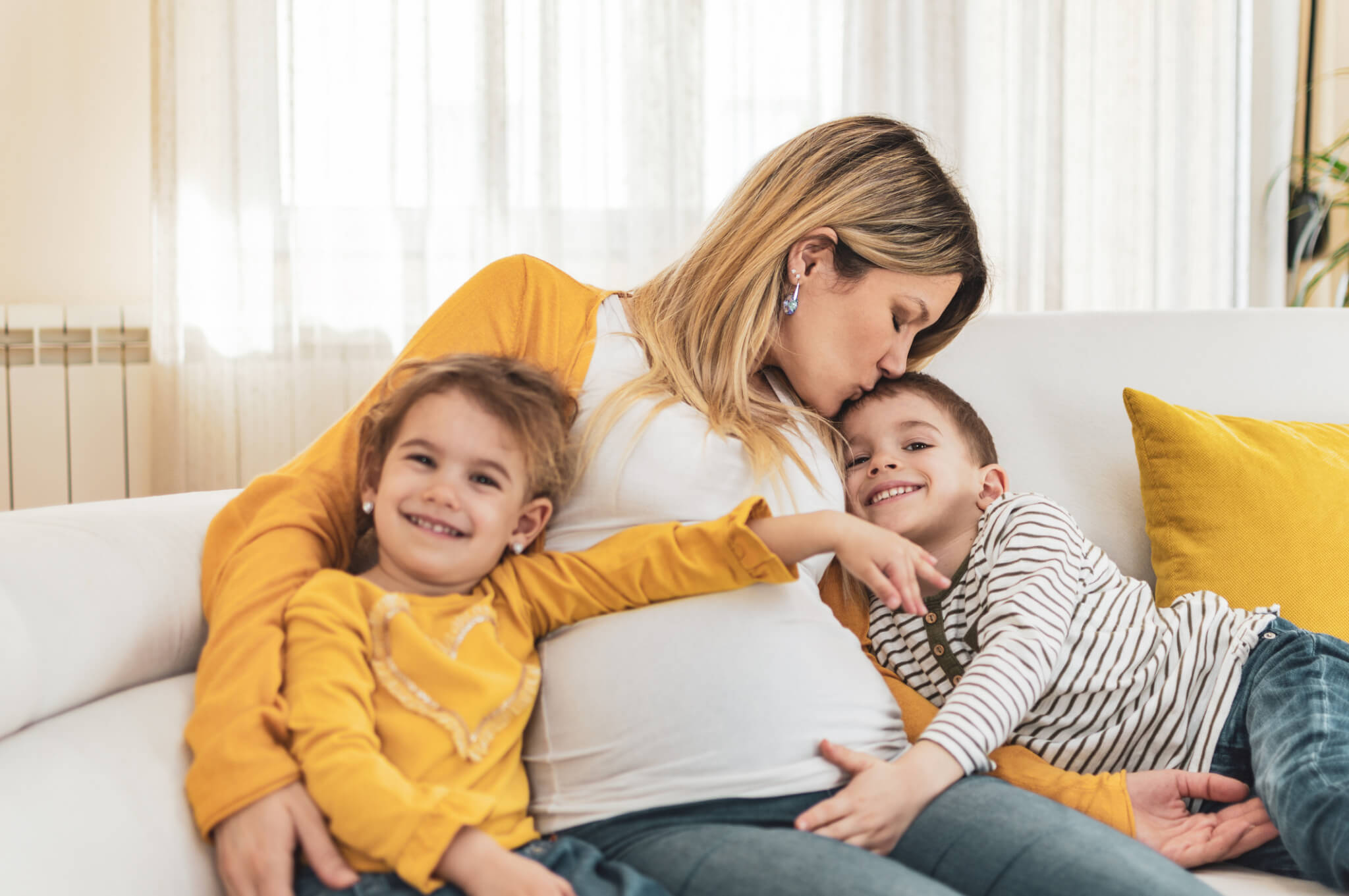 Happy mother and children,a boy and a girl are embracing pregnant belly with excitement on their faces.